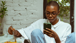 Junge Frau checkt ihr Handy: Aktien kaufen - so analysierst du Kurse im Schnell-Check