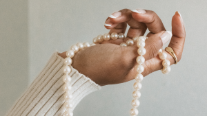 Hand einer person of colour mit Perlenkette Schmuck: Ist Schmuck eine gute Geldanlage?