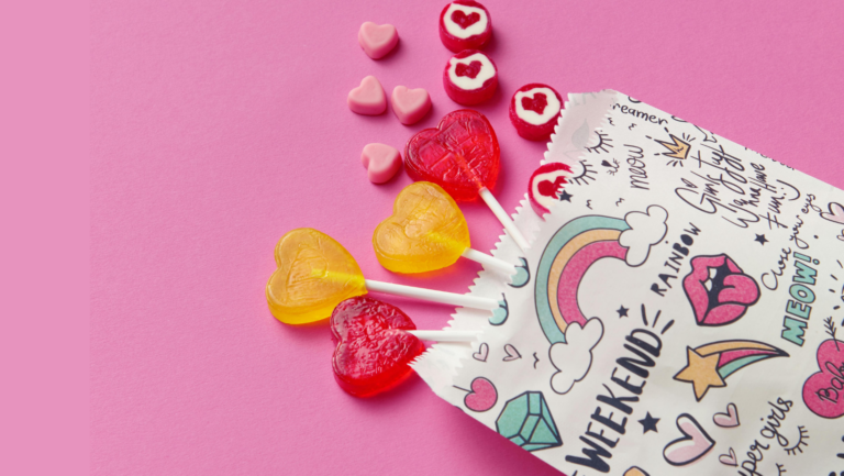 Eine bunte Tüte, aus der Herz-Lollies und bunte Herz-Bonbons fallen.