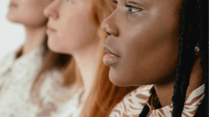 Drei Frauen im Profil, vorne eine schwarze Frau, dahinter eine rothaarige, die dritte Frau ist nur noch unscharf zu erkennen