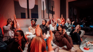 Die Frauen der Top 12 von Miss Germany sitzen auf einem Sofa und Fußboden und jubeln. Sie sind zum Mastermind Camp zusammengekommen.