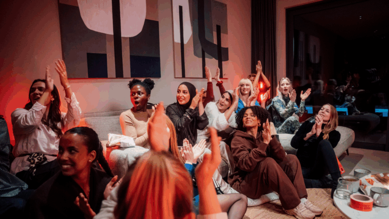 Die Frauen der Top 12 von Miss Germany sitzen auf einem Sofa und Fußboden und jubeln. Sie sind zum Mastermind Camp zusammengekommen.