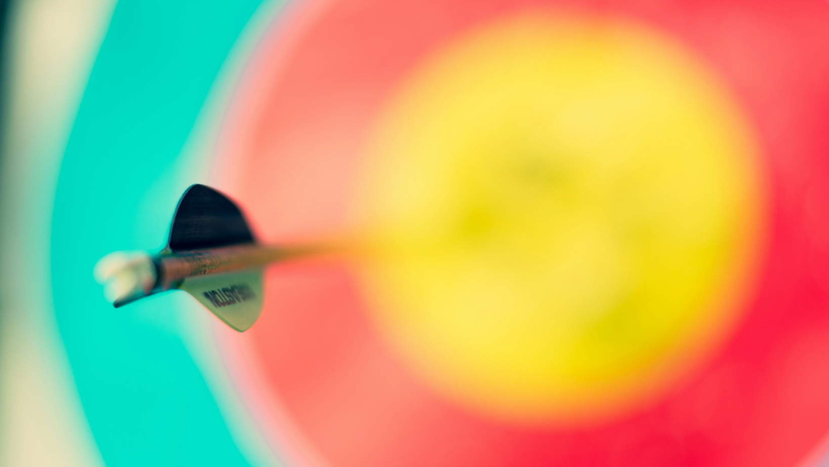 Eine verschwommene gelb-orange-grüne Zielscheibe mit einem Pfeil drin