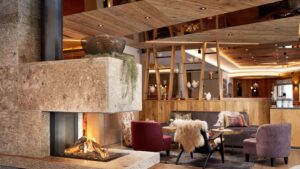 Aufnahme vom Alpin- und Spa-Hotel Tuxerhofi m Zillertal in Tirol: Im Vordergrund sieht man einen Kamin, im Hintergrund einen gemütlichen tisch mit Stühlen