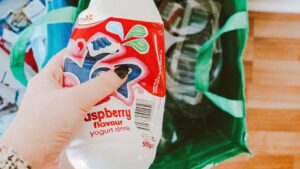 Eine Hand mit schwarz lackiertem Daumennagel hält eine PET-Flasche fest