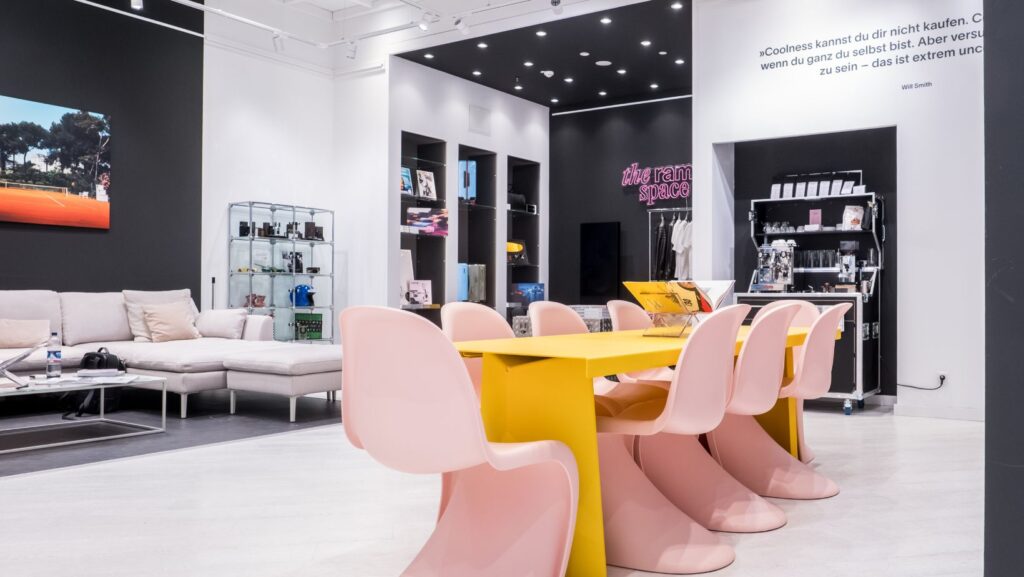 The Ramp Space im Dorotheen Quartier in Stuttgart: Man sieht einen gelben Tisch mit rosafarbigen Panton-Chairs von Vitra