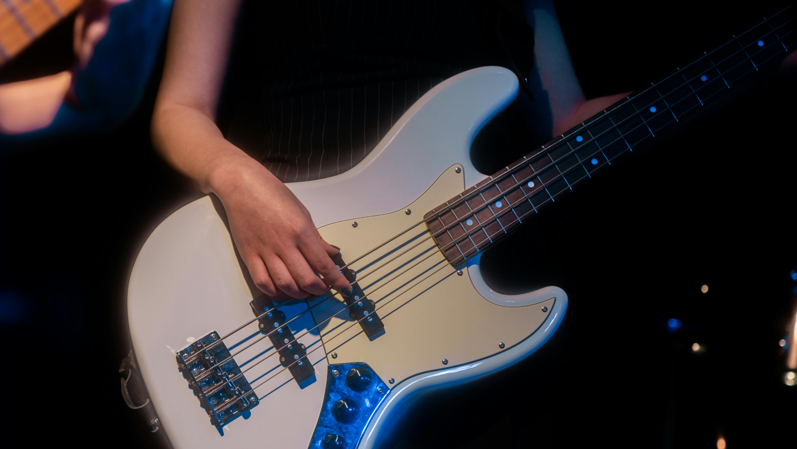 Weiße Gitarre und eine weibliche Hand, die an einer Seite zupft