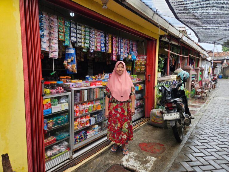 Eine indonesische Frau mit Kopftuch steht vor einem Marktstand