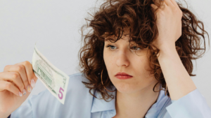 Frau mit Locken starrt auf einen Geldschein