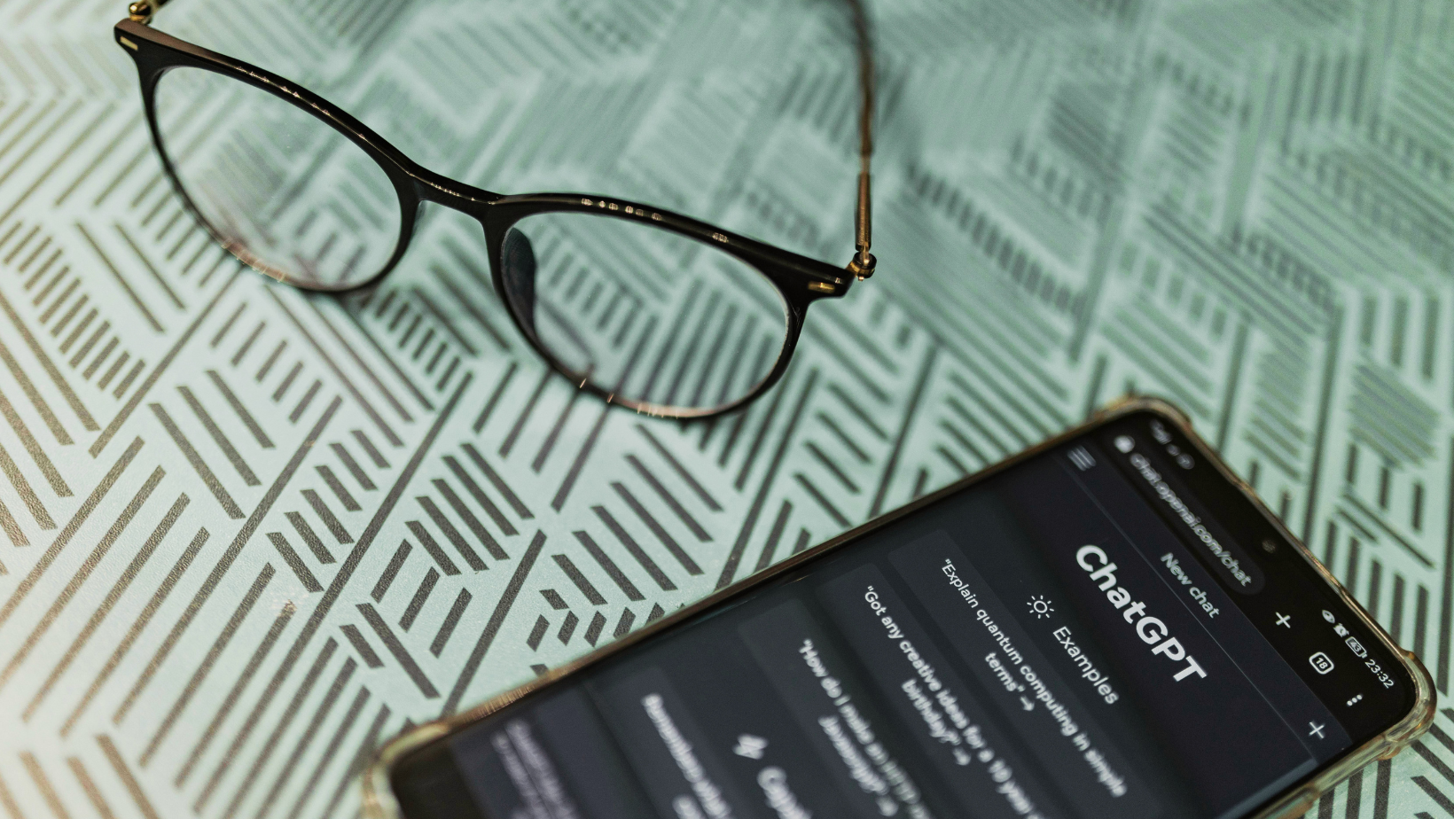 Als Symbolbild für Agentic Finance wird hier ein Smartphone mit Chat GPT gezeigt, daneben eine Brille.