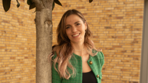 Ira Stoll, Ärztin und Gründerin von myscribe, lehnt an einen Baum und lächelt in die Kamera.