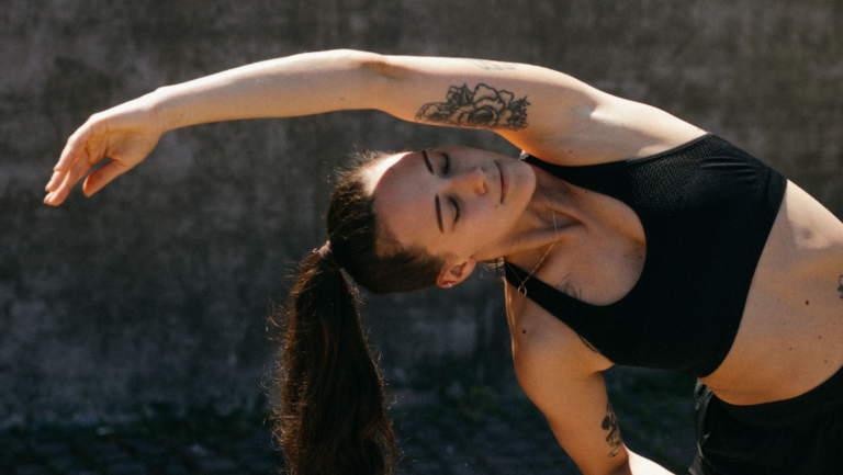 Eine Frau im Sport-Outfit dehnt sich mit dem Arm zur Seite