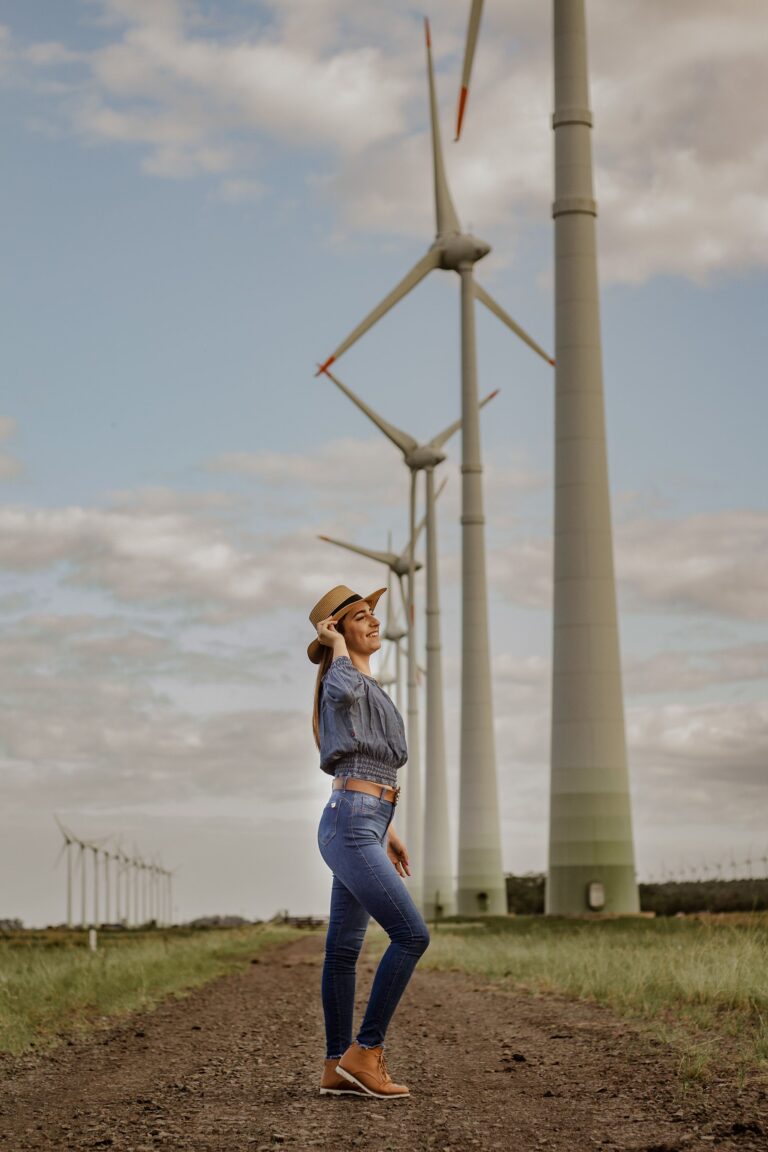 Frau steht entspannt vor Windrädern