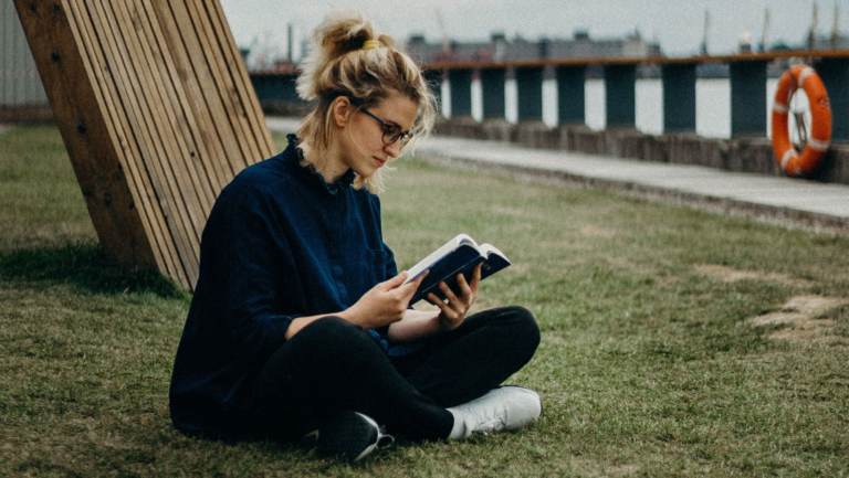 Eine junge Frau sitz am Fluss und liest